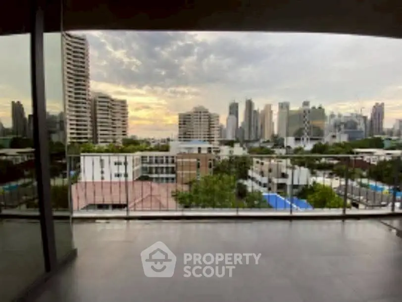 Spacious balcony with stunning city skyline view at sunset, perfect for urban living.