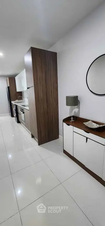 Sleek modern kitchen with white tiles and wooden cabinetry, featuring a built-in oven and stylish decor.
