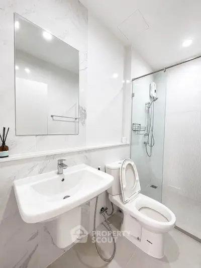 Modern bathroom with sleek fixtures and glass shower enclosure in a contemporary home.