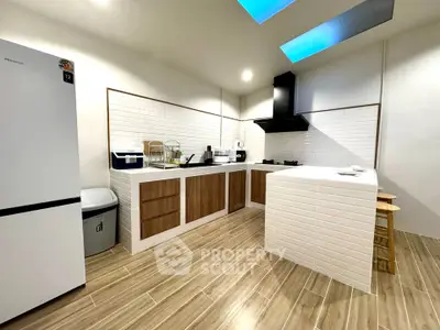 Modern kitchen with sleek design, featuring wooden cabinets, white brick tiles, and skylights for natural lighting.