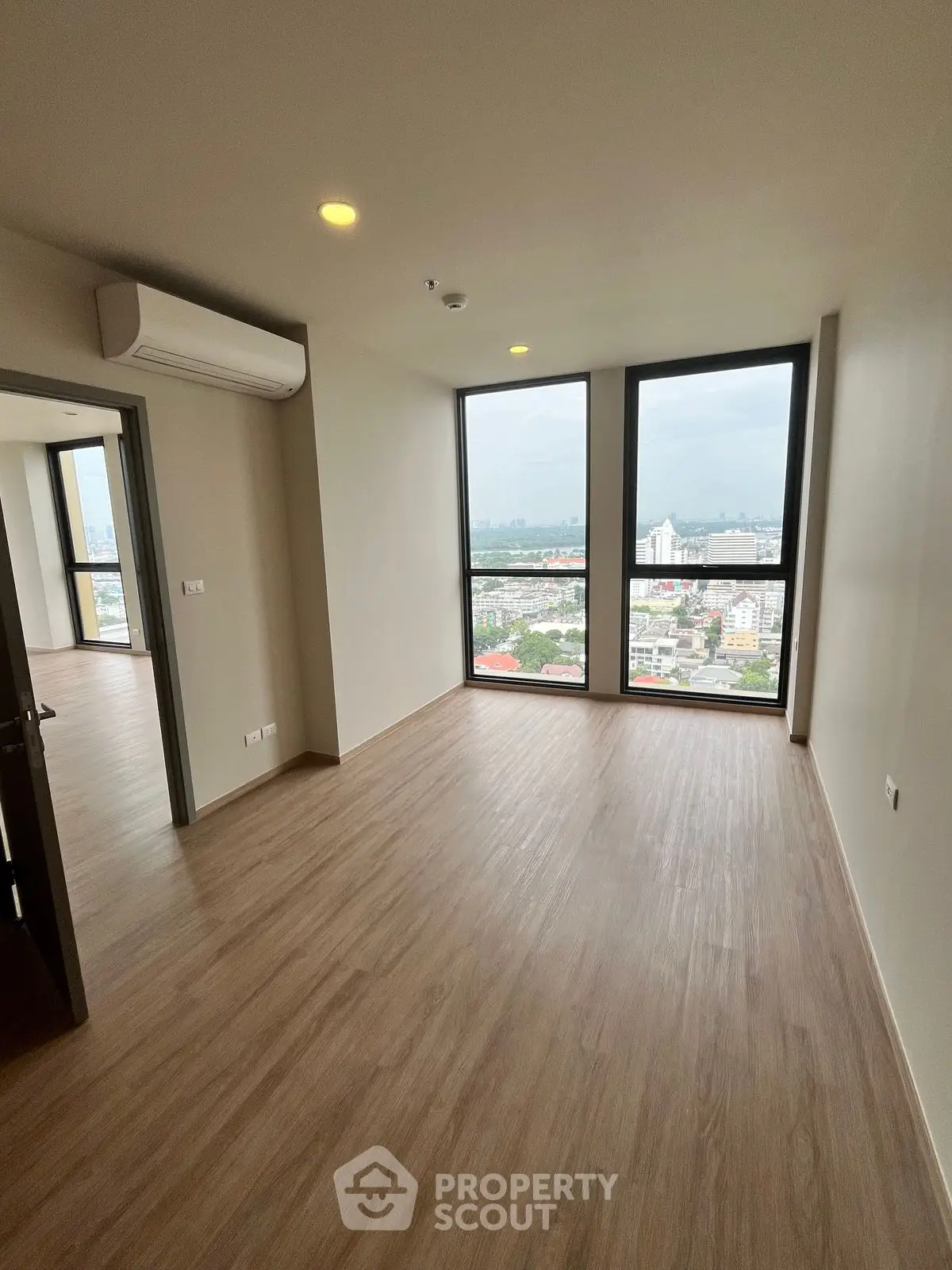 Spacious empty room with large windows offering stunning city views, perfect for modern living.