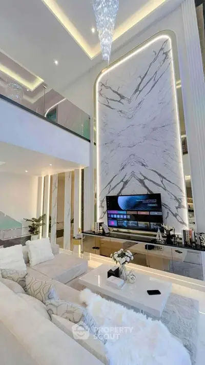 Luxurious modern living room with high ceilings and elegant marble wall design.