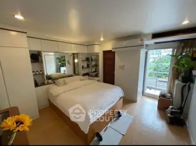 Spacious bedroom with balcony and modern decor in urban apartment