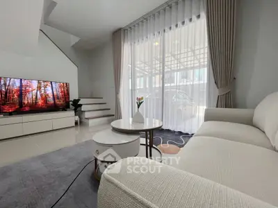 Modern living room with elegant decor, large window, and cozy seating area.