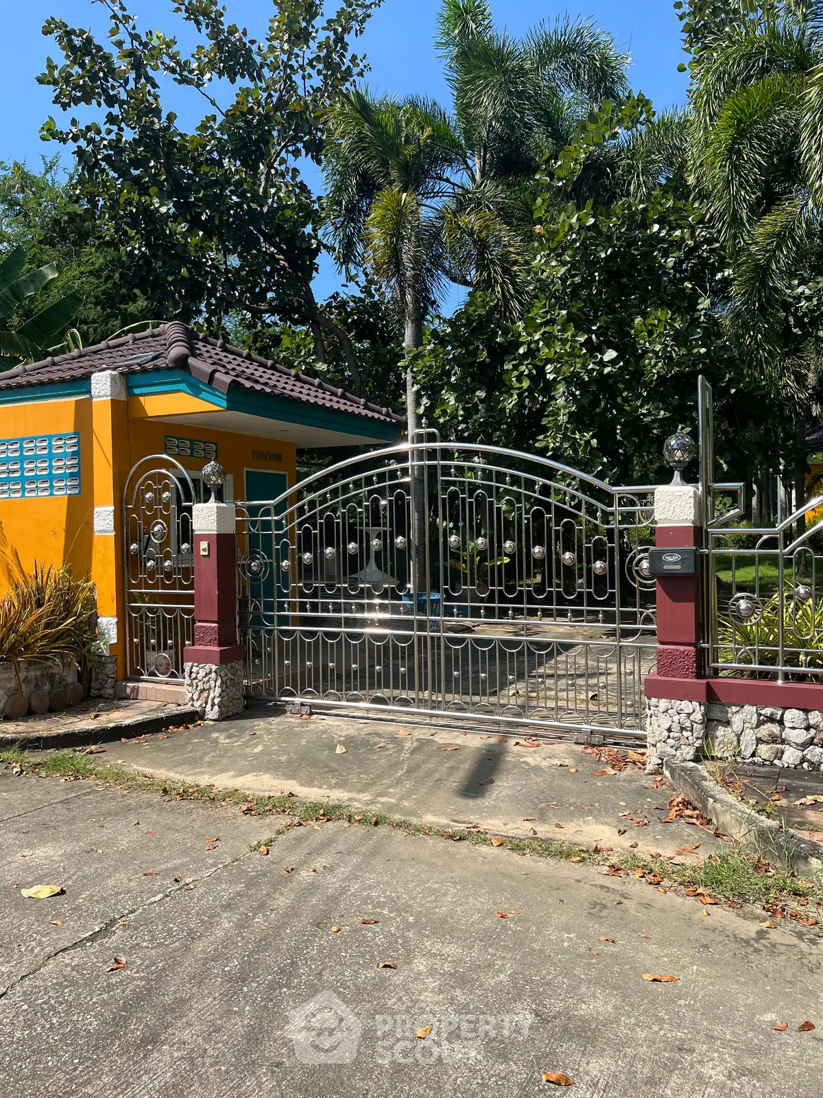 Charming gated entrance to a colorful tropical home with lush greenery