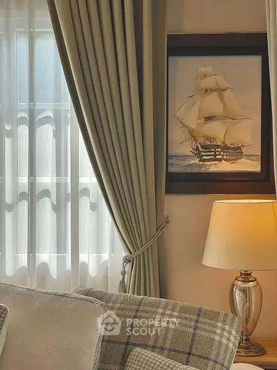 Elegant living room with classic decor, featuring plush sofa, nautical artwork, and ambient lighting.