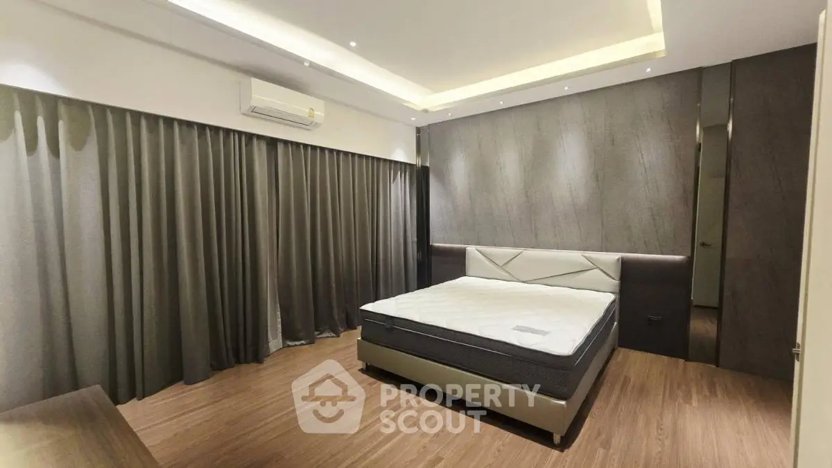 Spacious modern bedroom with elegant design and ambient lighting, featuring a comfortable bed and sleek wooden flooring.