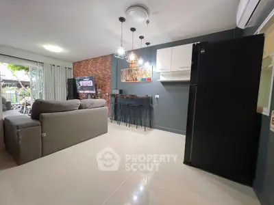 Modern living room with open kitchen, stylish decor, and cozy seating area.