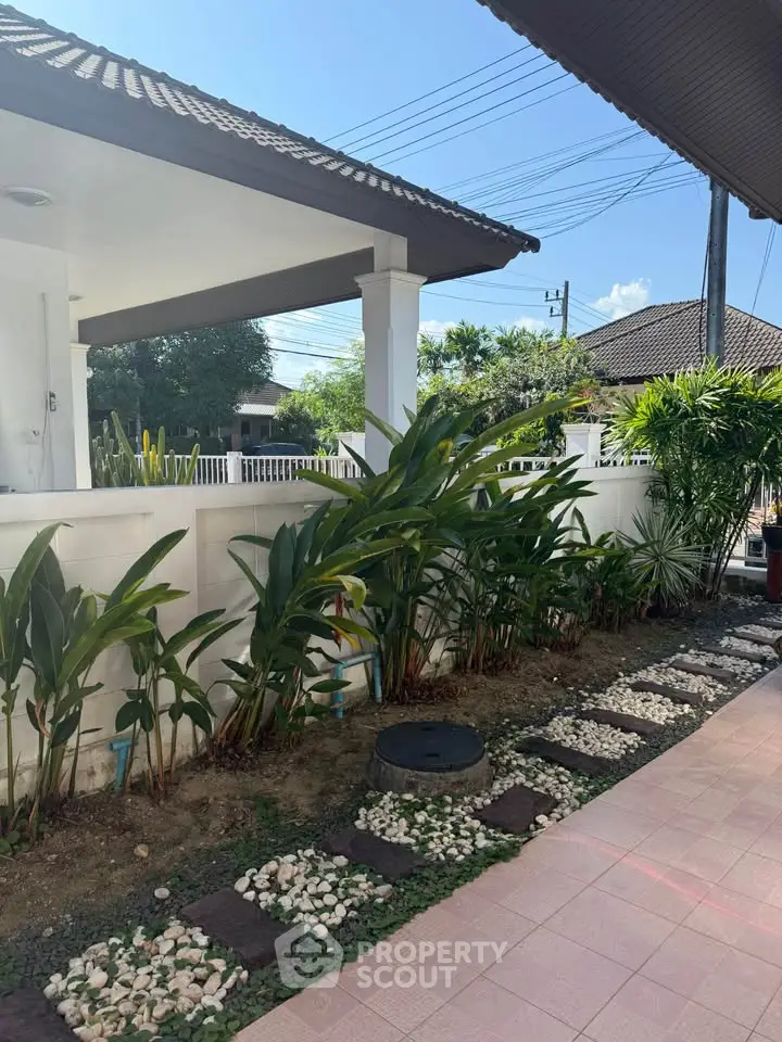 Charming garden view of a suburban home with lush greenery and tiled pathway, perfect for relaxation.