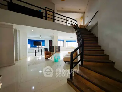 Spacious modern living room with open staircase and natural light