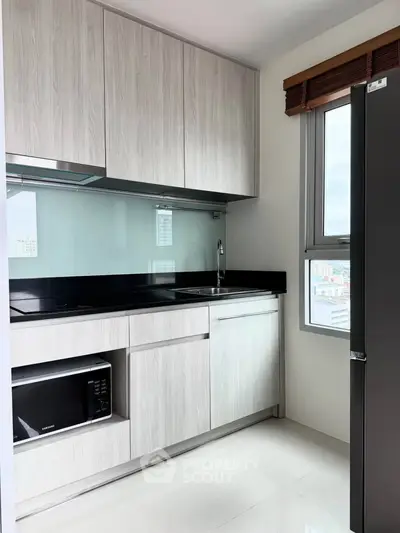 Modern kitchen with sleek cabinetry and large window offering city views.