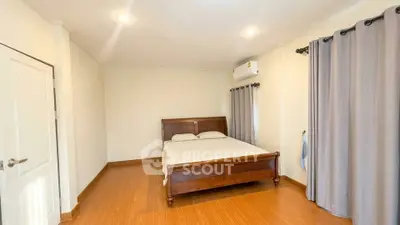 Spacious bedroom with wooden flooring and modern air conditioning unit.