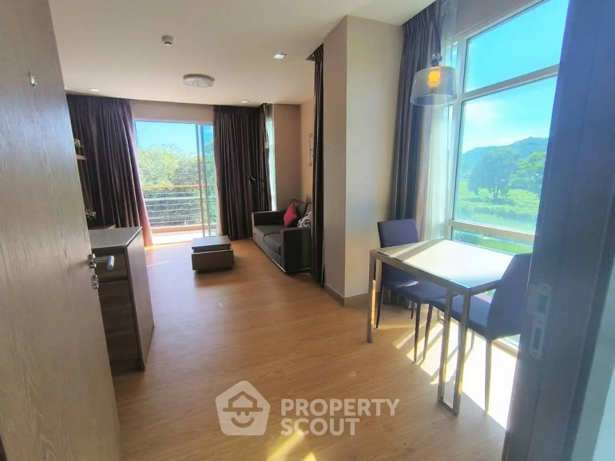 Bright and spacious living room with large windows and scenic view, featuring modern furniture and dining area.