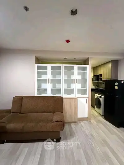 Modern living room with stylish sofa and sleek kitchen appliances in open layout.