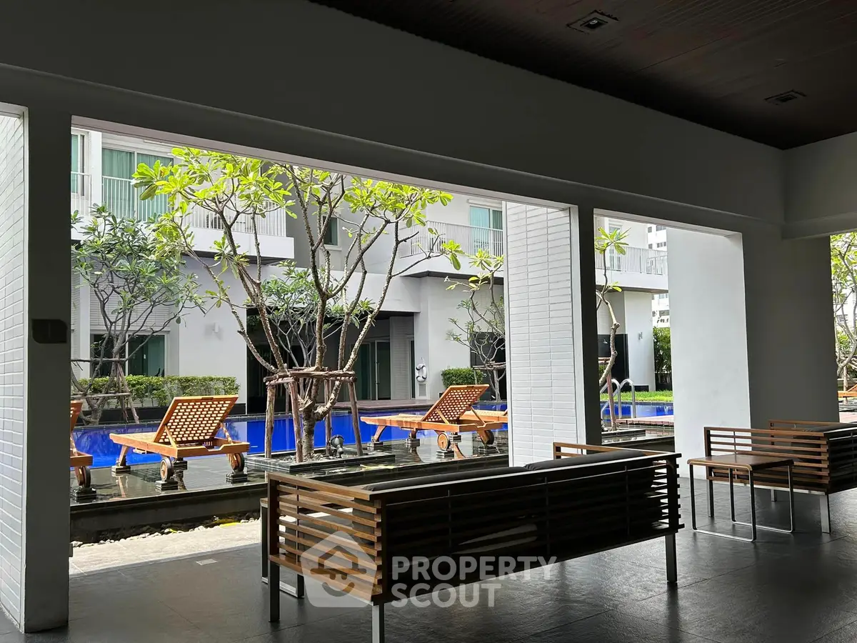 Modern outdoor seating area with pool view in luxury apartment complex