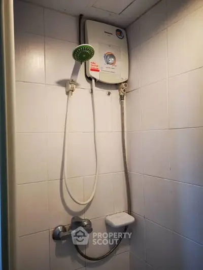 Compact bathroom shower area with water heater and tiled walls