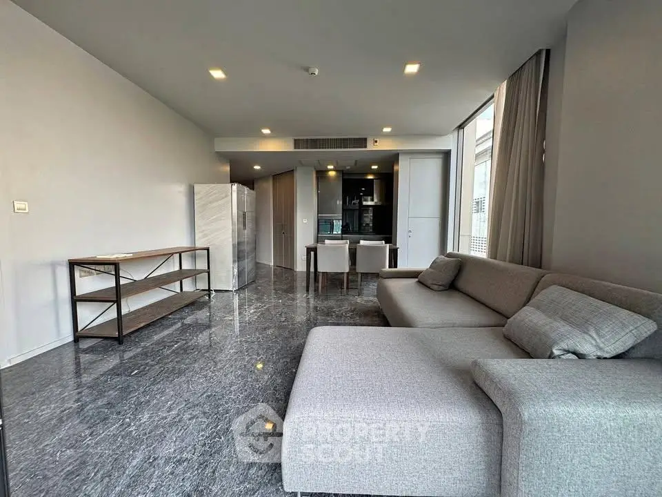 Spacious modern living room with sleek gray sofa and open kitchen layout.