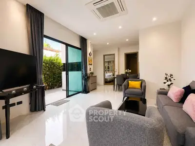 Modern living room with sleek furniture and large TV, featuring open layout and natural light.