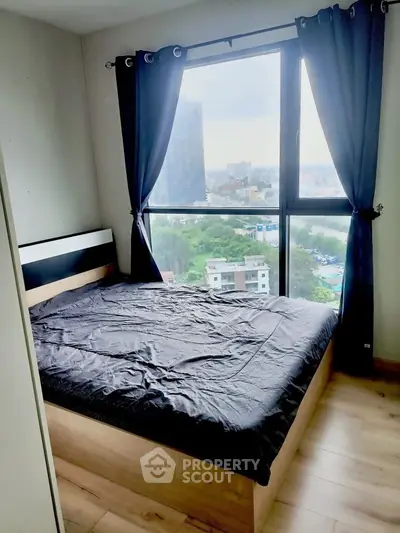 Cozy bedroom with large window offering stunning city view, featuring modern decor and natural light.