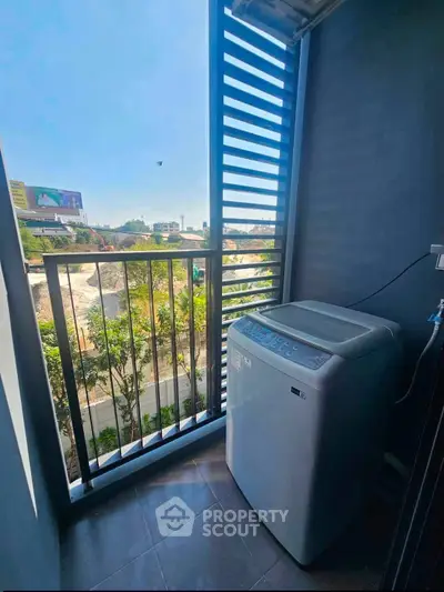 Compact balcony with washing machine and scenic view, ideal for urban living convenience.