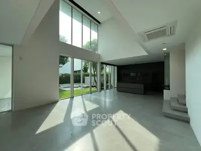 Spacious modern living room with high ceilings and large windows overlooking garden.