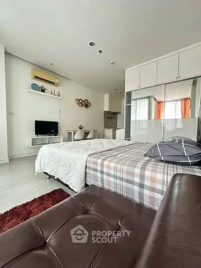 Modern studio apartment with stylish decor and open layout, featuring cozy bed and compact kitchen area.