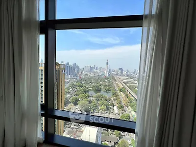 Stunning cityscape view from high-rise apartment window with lush greenery and skyline.