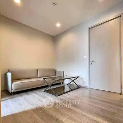 Modern minimalist living room with sleek sofa and glass coffee table on wooden flooring.