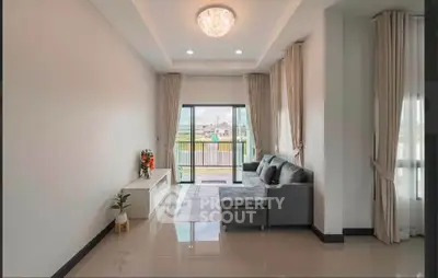 Spacious living room with modern decor and large windows leading to a balcony with a view.