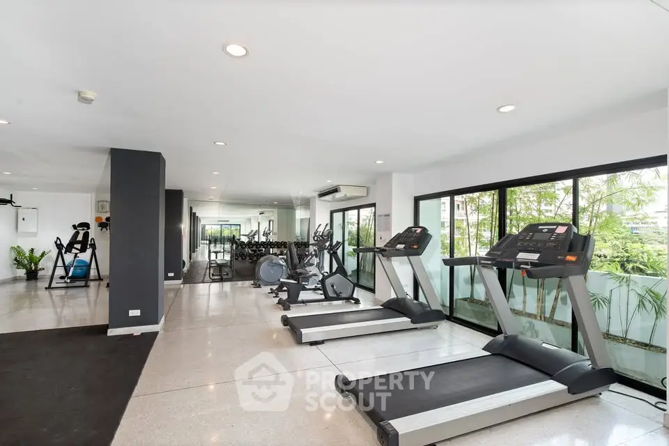 Spacious modern gym with state-of-the-art equipment and large windows offering natural light.