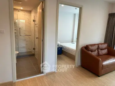 Modern apartment interior with cozy living area and adjacent bedroom, featuring a sleek bathroom design.