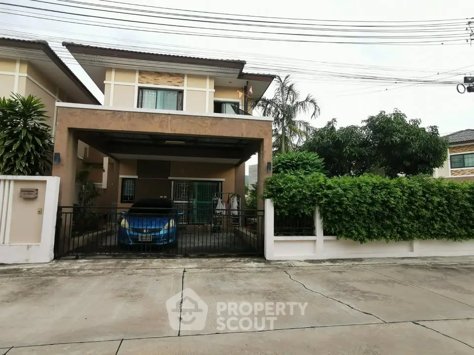 Charming two-story house with carport and lush greenery in a serene neighborhood.