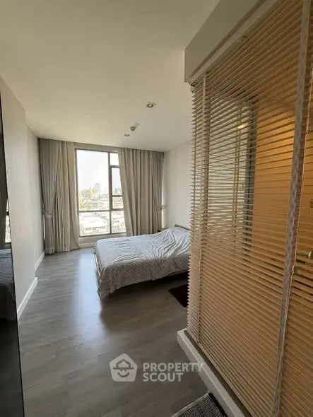 Modern bedroom with city view and stylish decor, featuring large window and cozy ambiance.