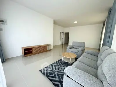 Spacious modern living room with cozy gray sofa and stylish wooden furniture.