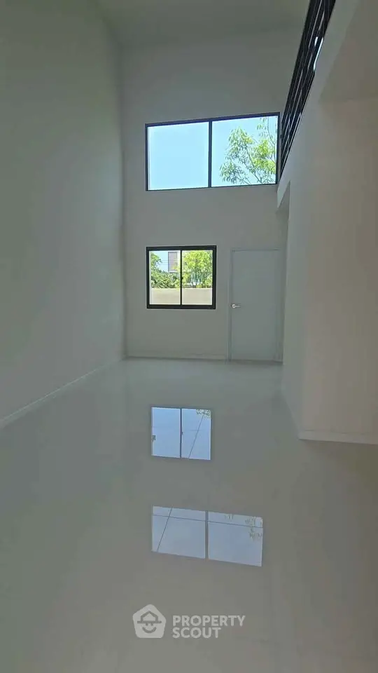 Spacious modern interior with high ceilings and large windows offering natural light.