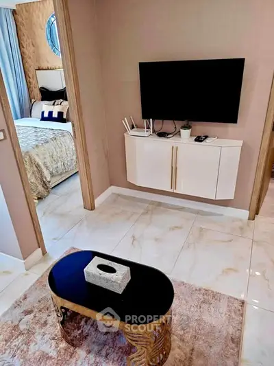 Modern living room with sleek TV setup and view into elegant bedroom