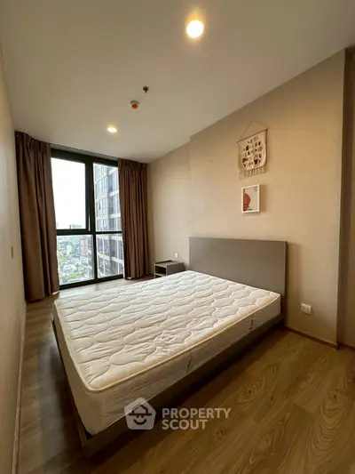 Spacious bedroom with large window and modern decor in high-rise apartment