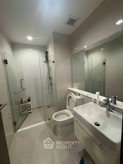 Modern bathroom with glass shower and sleek fixtures in contemporary apartment.