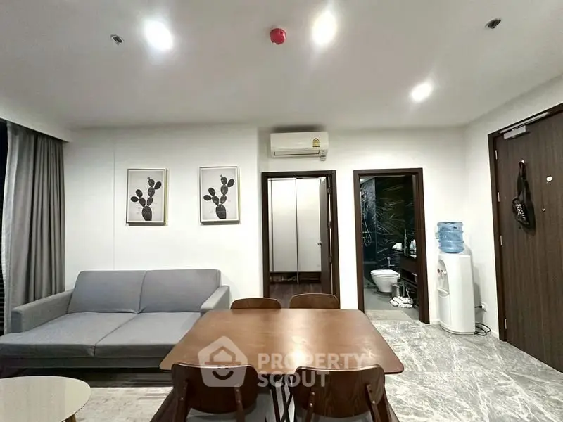 Modern living room with dining area, featuring sleek furniture and contemporary decor.