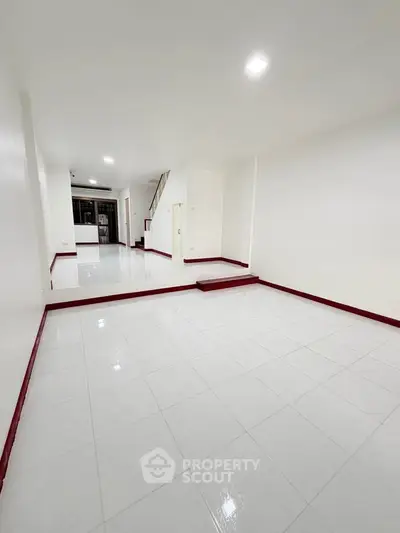 Spacious white-tiled interior with elevated platform and modern lighting, ideal for versatile living space.