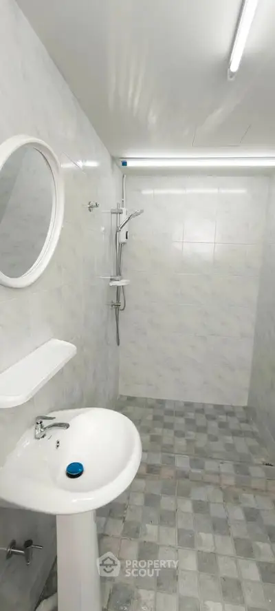 Modern minimalist bathroom with white fixtures and tiled walls, featuring a sleek shower area.