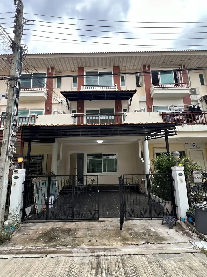 Charming townhouse exterior with gated entrance and balcony, perfect for modern living.