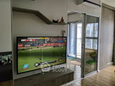 Modern living room with TV and sliding glass doors leading to a balcony in a stylish apartment.
