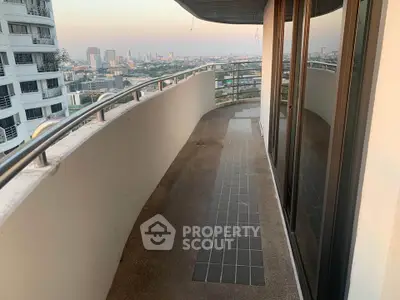 Spacious curved balcony with city skyline view in modern high-rise apartment.