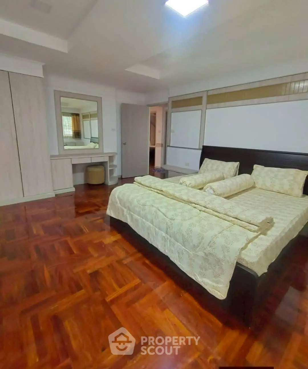 Spacious bedroom with elegant wooden flooring and cozy bedding