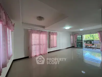 Spacious living room with pink curtains and balcony access, perfect for family gatherings.