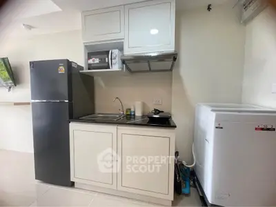 Modern compact kitchen with appliances including fridge, microwave, and washing machine in a sleek design.