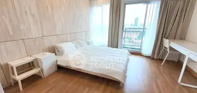 Spacious bedroom with modern decor and city view balcony in luxury apartment.