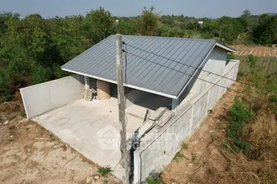 Modern single-story house with metal roof and spacious yard in a serene rural setting.