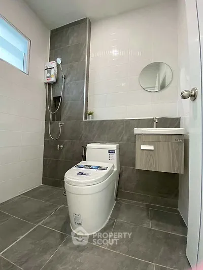 Modern bathroom with sleek design, featuring a toilet, sink, and shower area with stylish tiles.